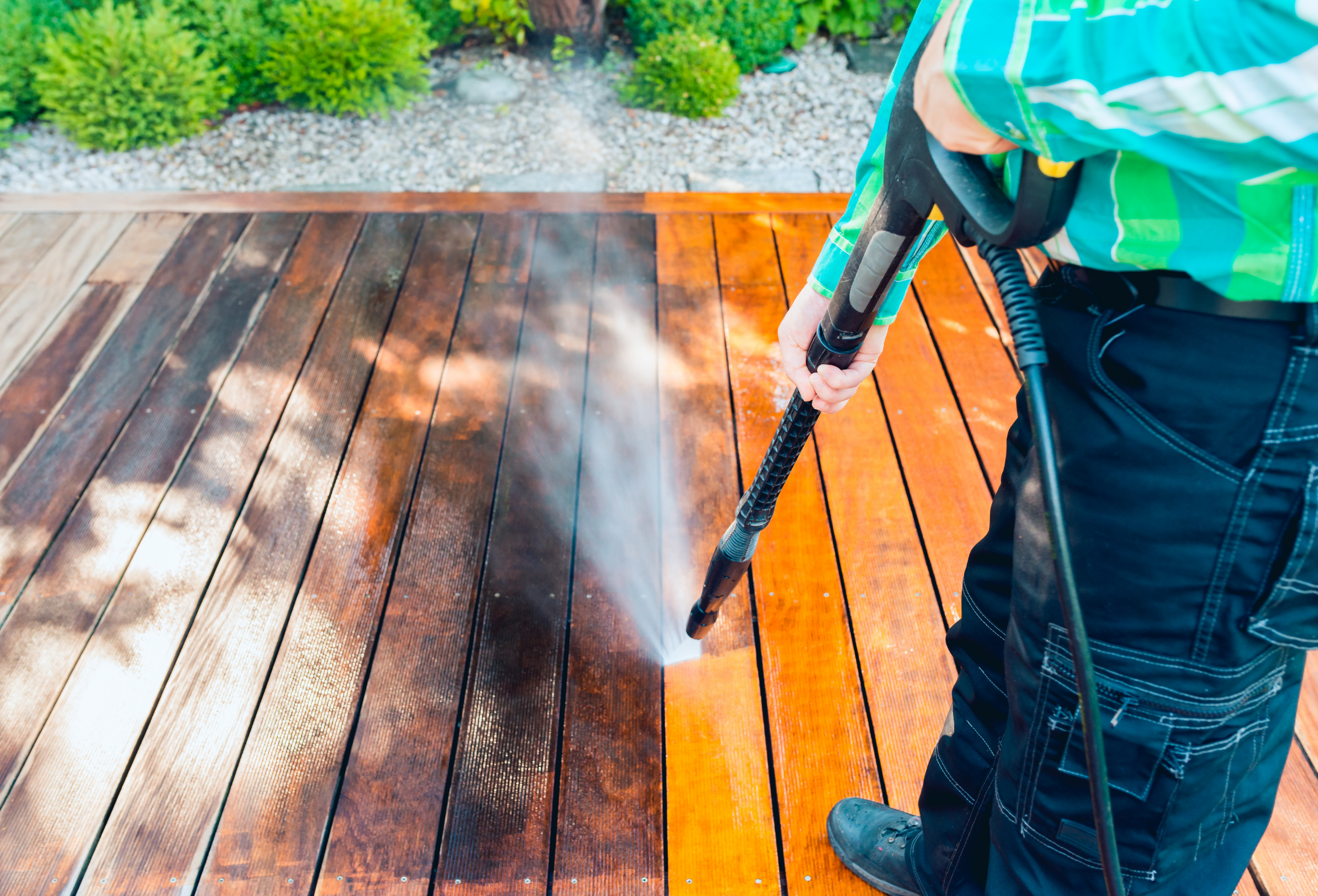 A man pressure washing a patio, revealing a clean surface as the water removes dirt and grime, showing the effectiveness of pressure cleaning.